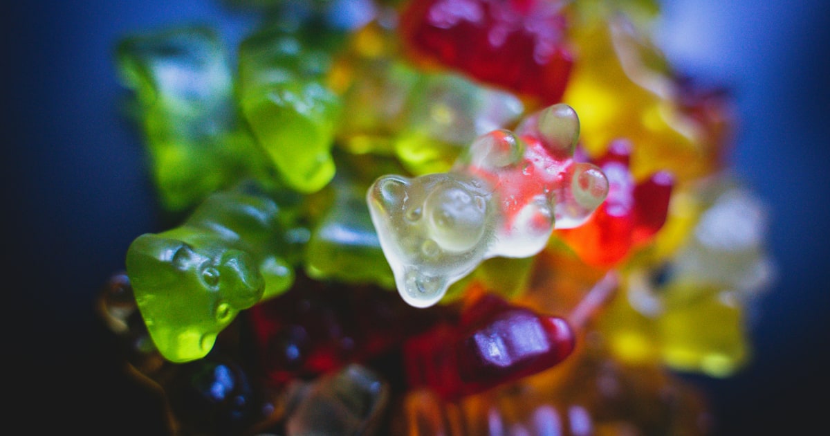 Colourful gummy bears in red, green, yellow, and orange scattered on a surface