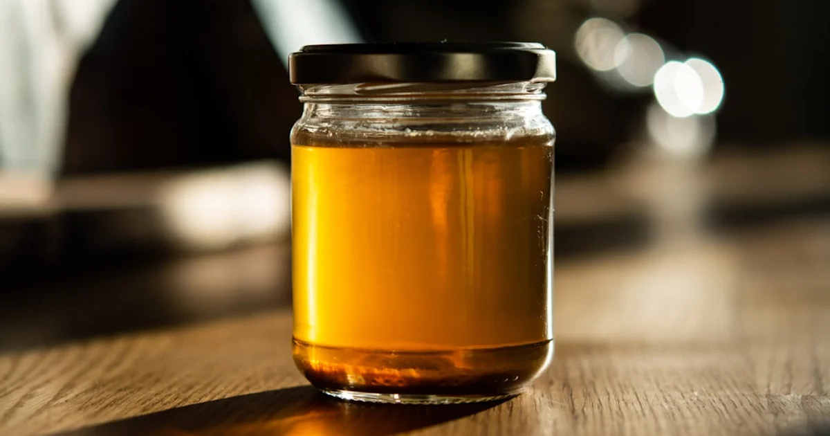 Glass jar of golden bone broth on a wooden kitchen table