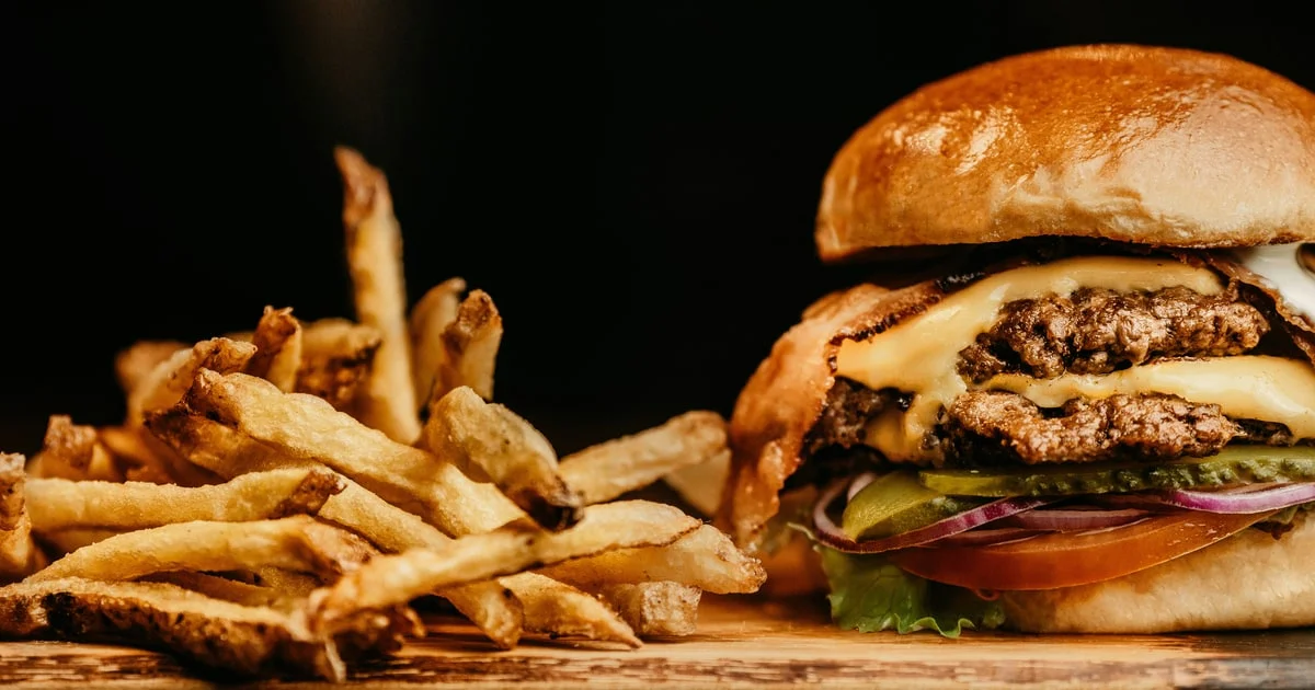 Double smash burger with melted cheese and fries on a paper-lined tray