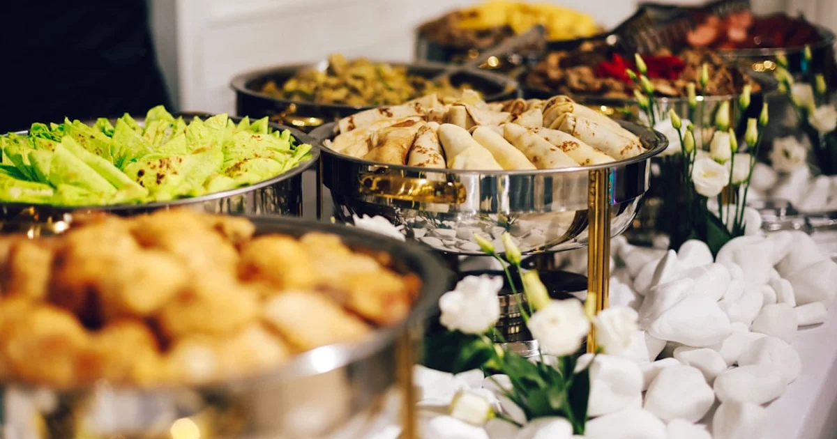 Buffet catering trays of flatbread, salad, and appetizers on chafing dishes at an event