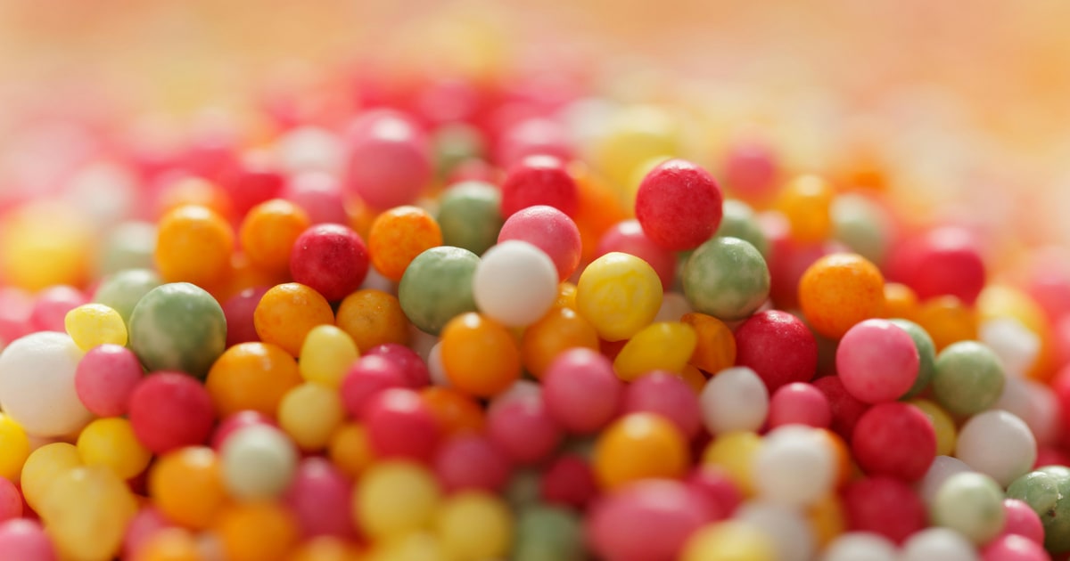 Colourful jelly beans with shiny shellac glaze coating on a white background