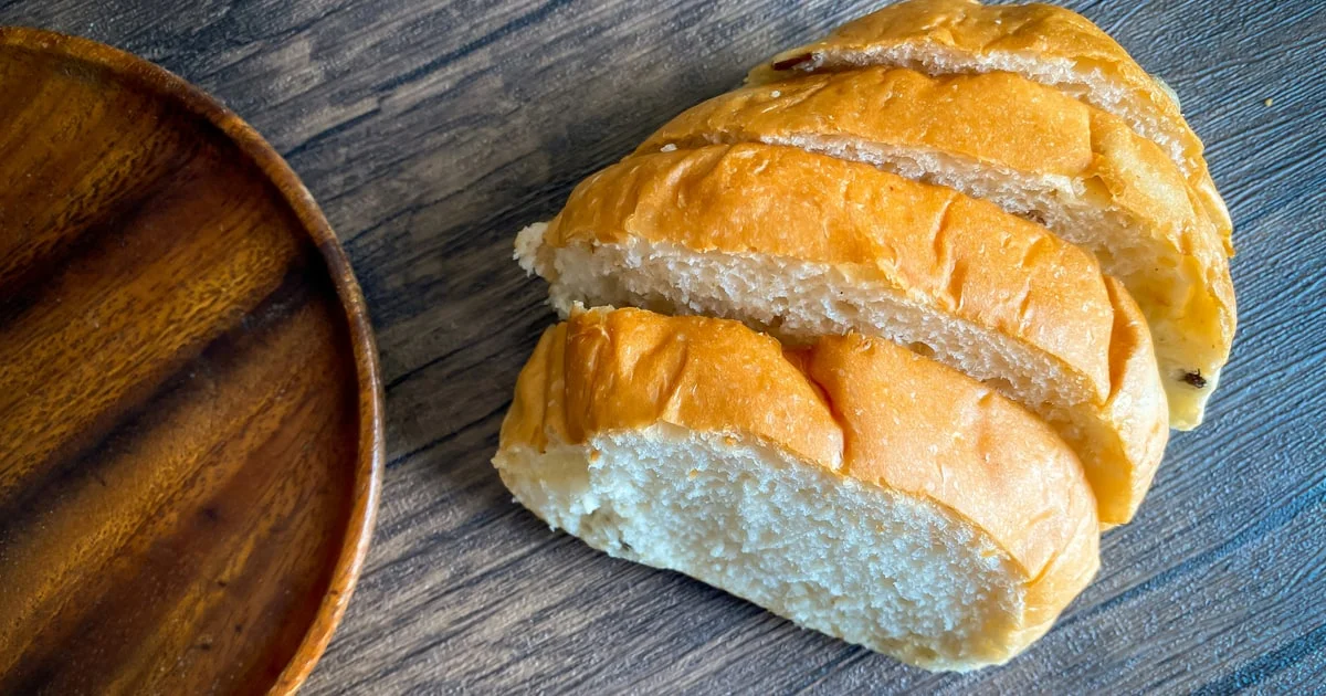 Sliced white bread loaf and bread rolls on a table