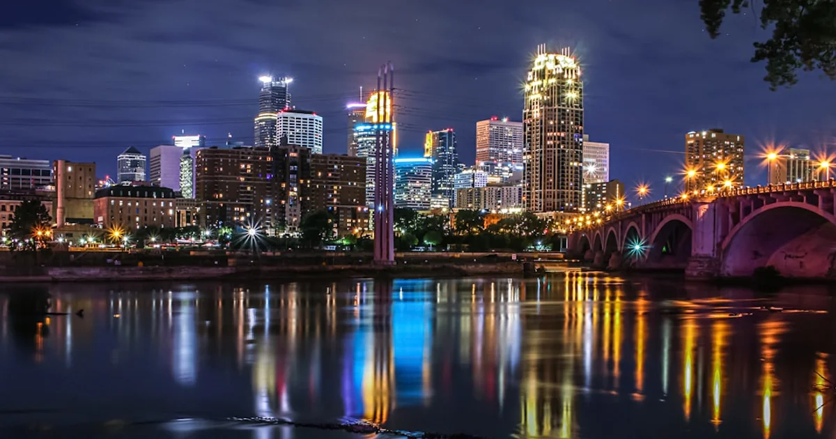 Minneapolis downtown skyline and bridge lit up at night over the Mississippi River