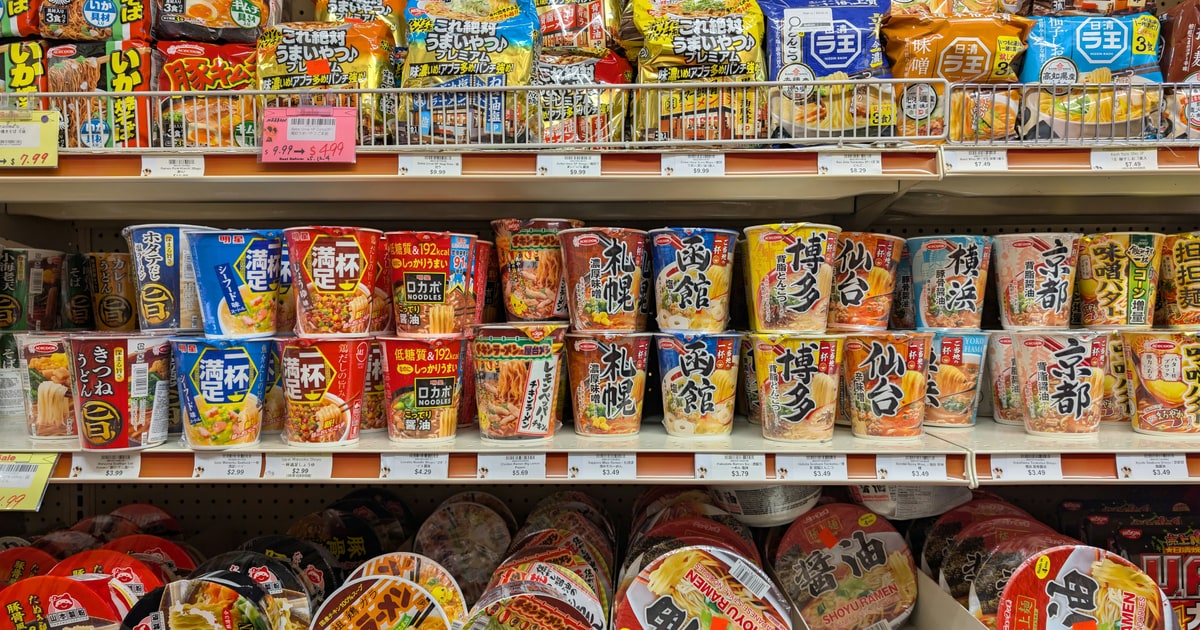 Several instant noodle cups and packets from different brands arranged on a kitchen counter