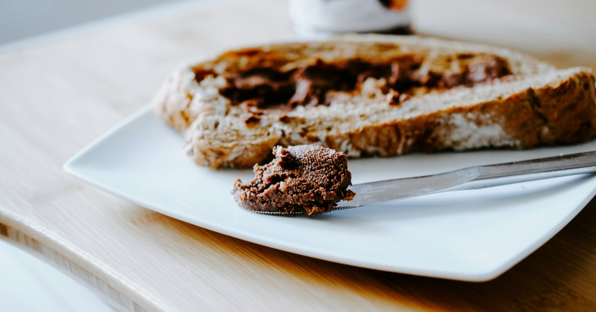 Jar of Marmite yeast extract spread on a kitchen counter with bread in the background