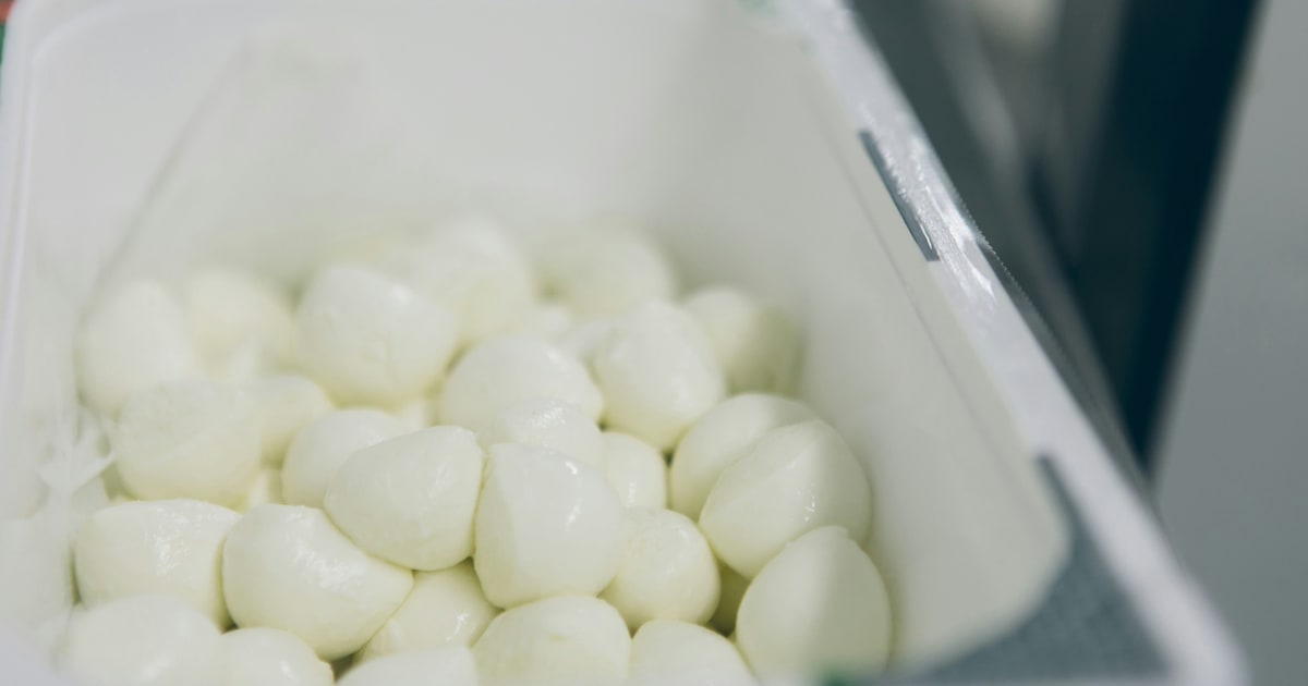 Fresh mozzarella ball in brine with packaging showing vegetarian mark