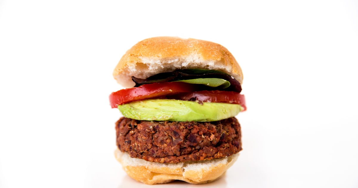 Plant-based burger patties and meat alternatives displayed with fresh vegetables on a wooden board