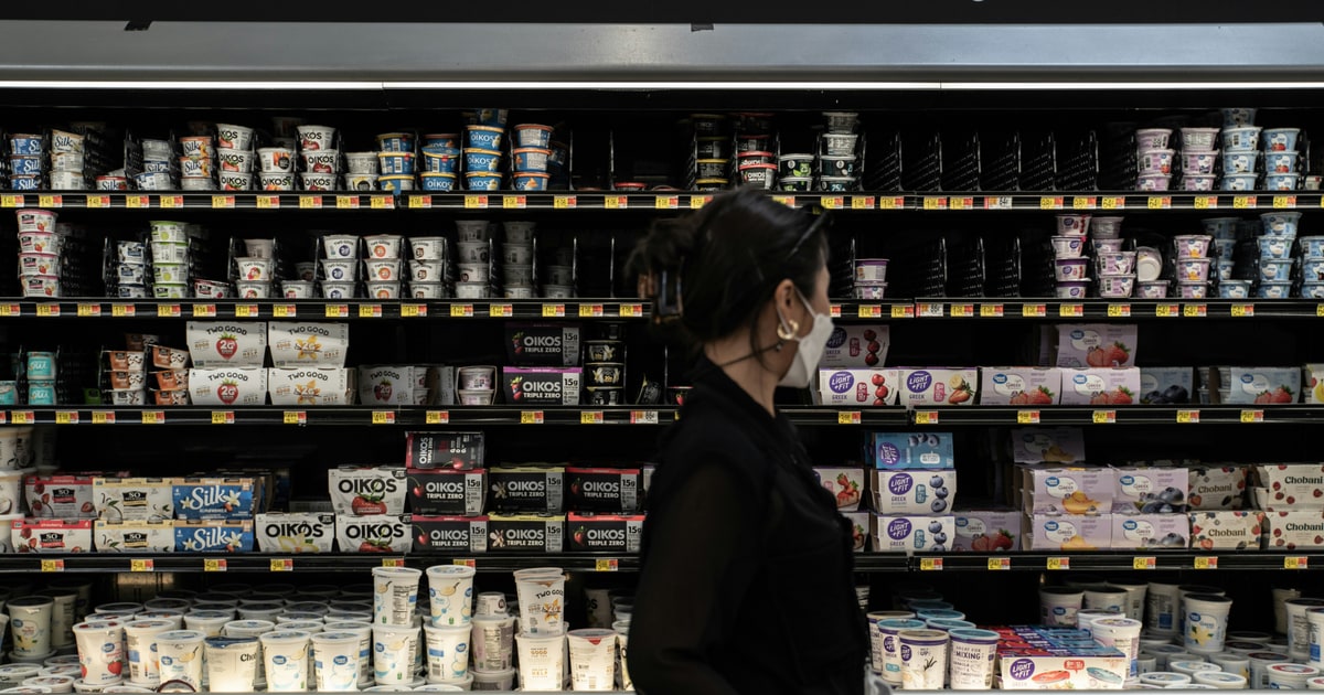 Supermarket yoghurt aisle with various fruit yoghurt pots showing E120 warning