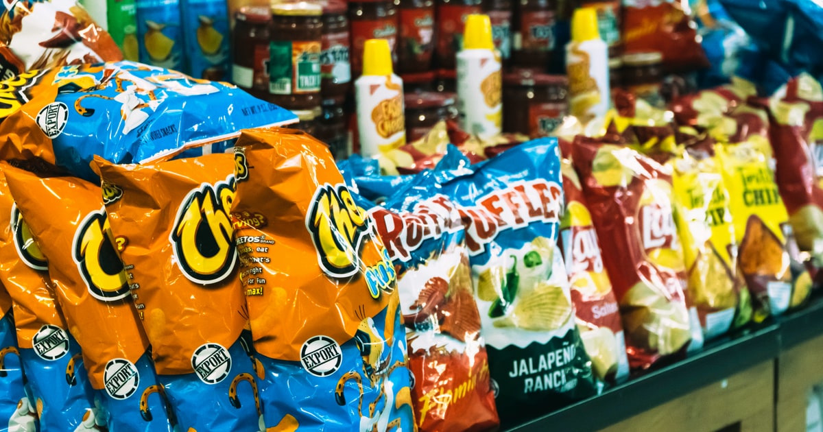 Assortment of snack foods including crisps, gummy sweets and biscuits with E-code labels